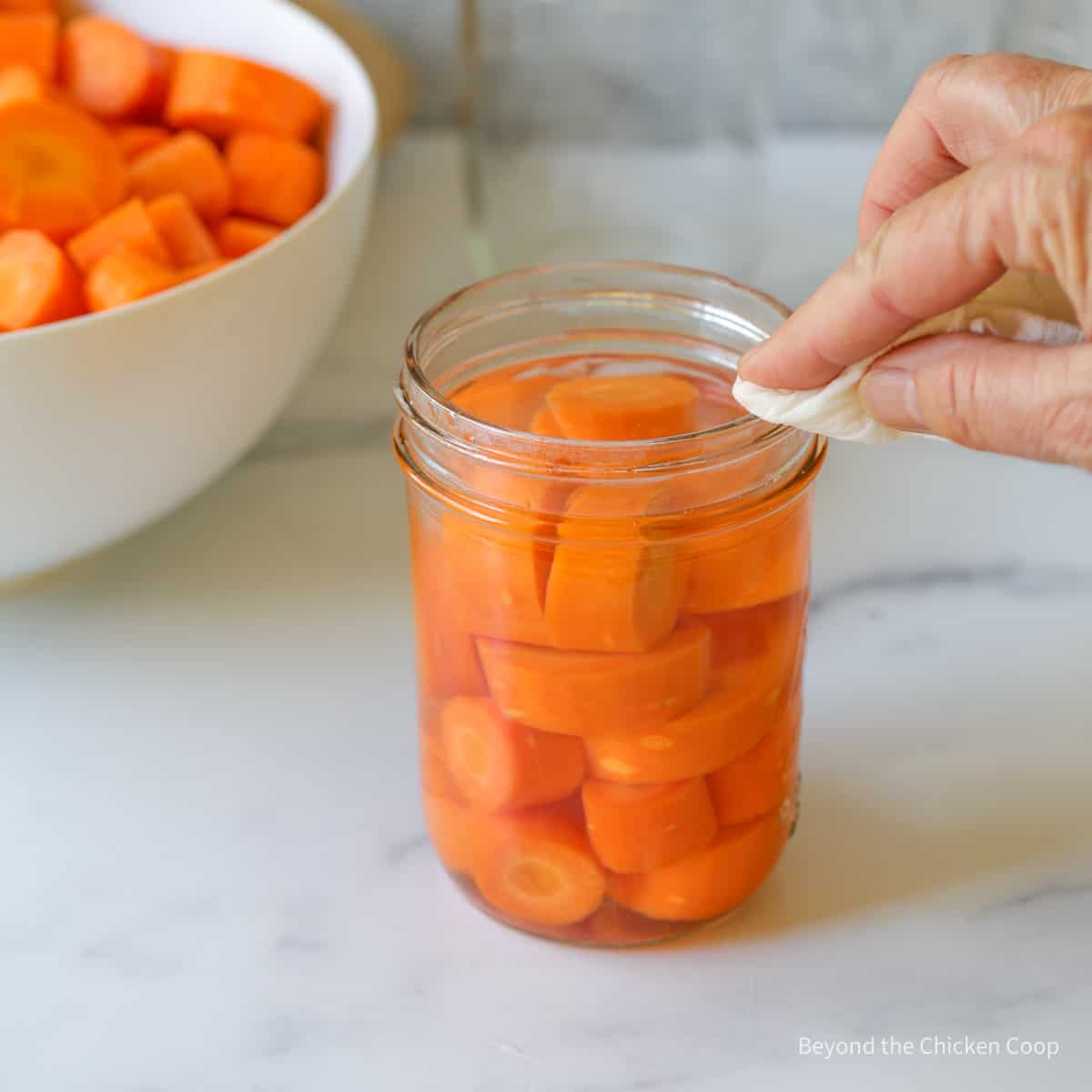 Wiping the rim of a canning jar.