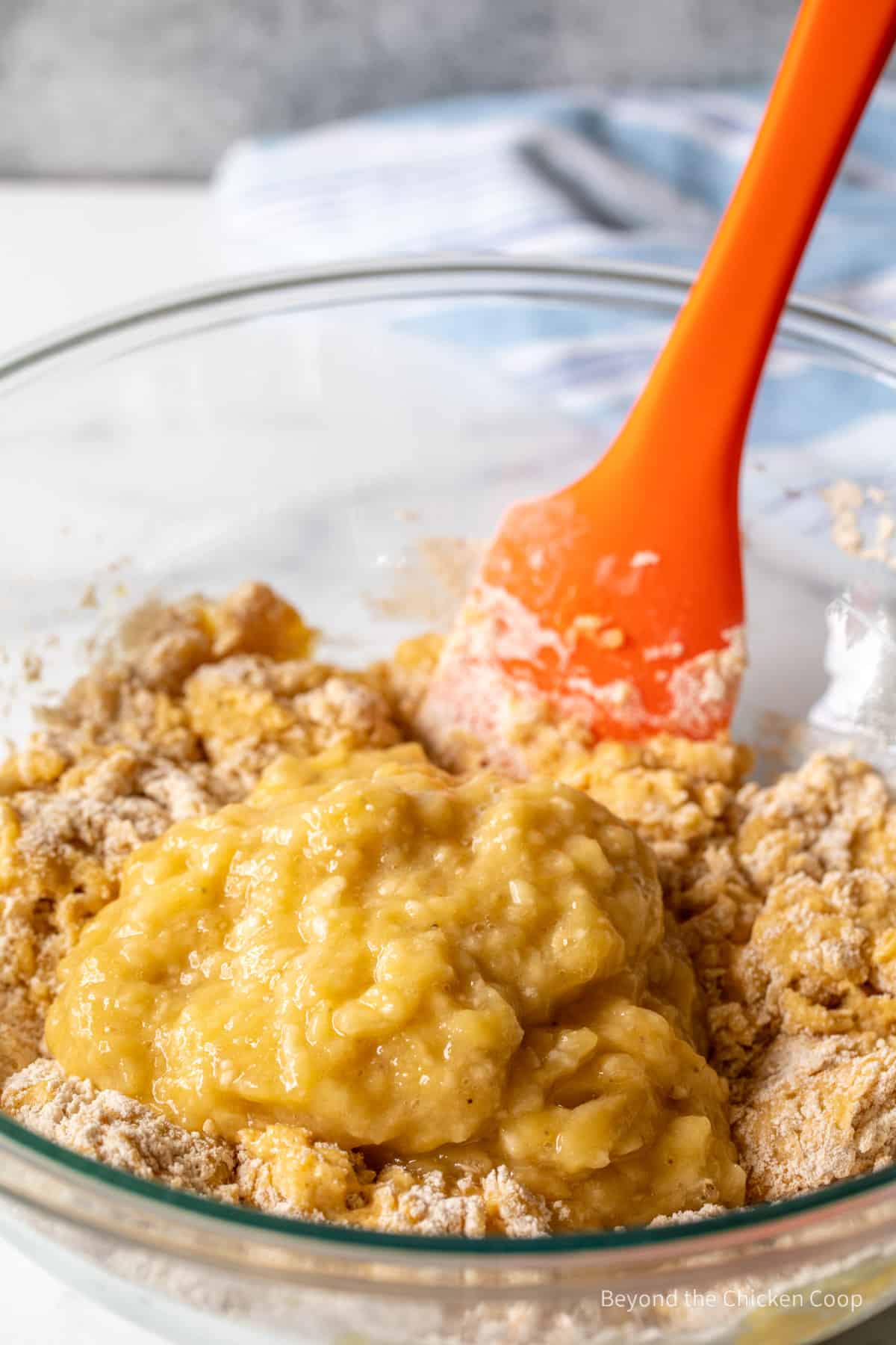 Adding mashed bananas to muffin batter.