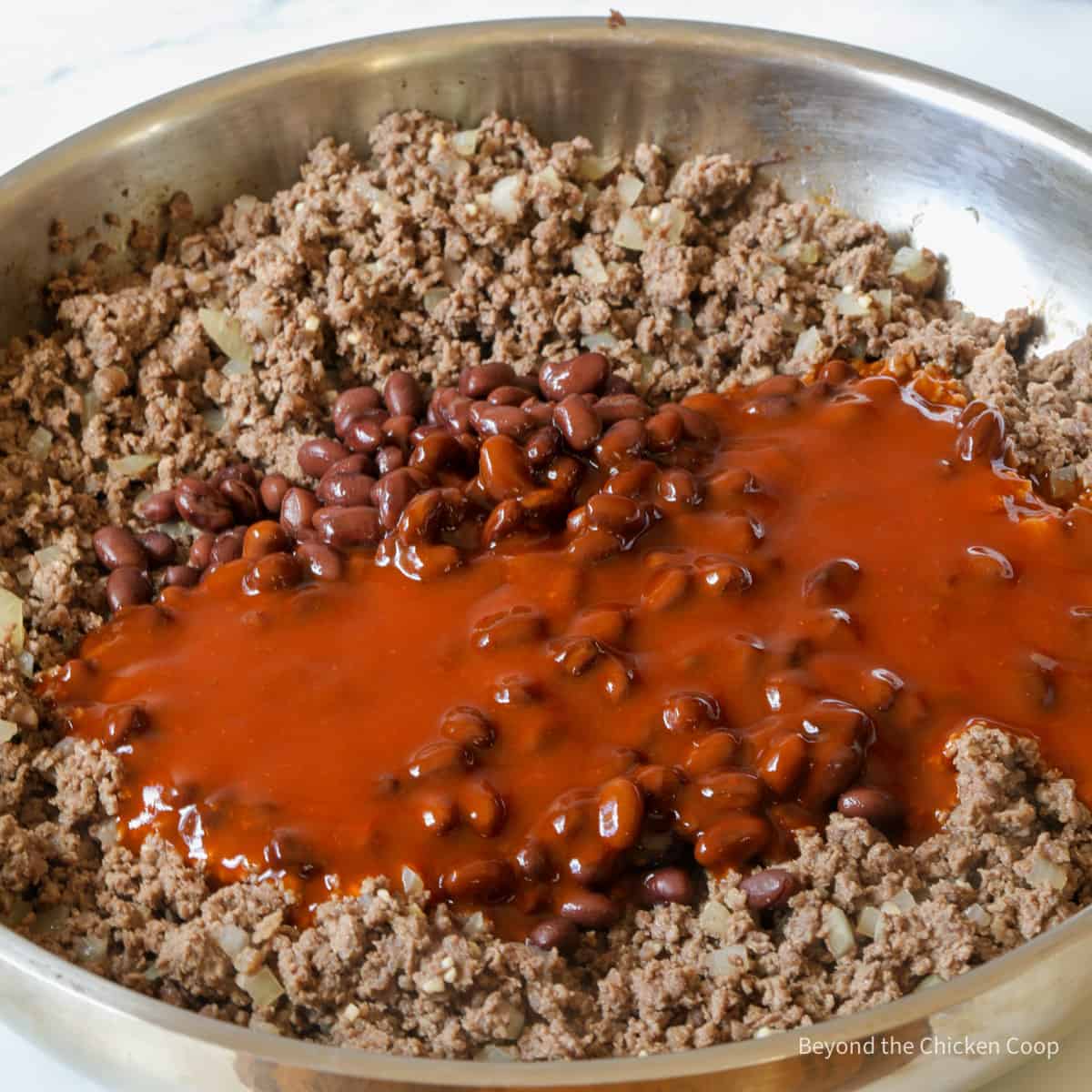 Adding enchilada sauce to ground burger.