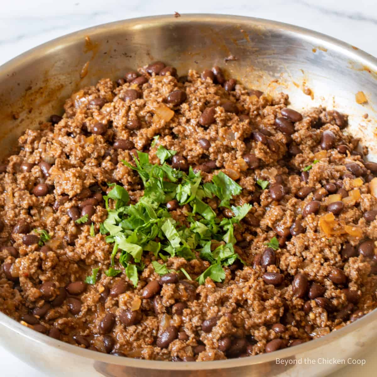 Fresh cilantro in a pan with ground beef.