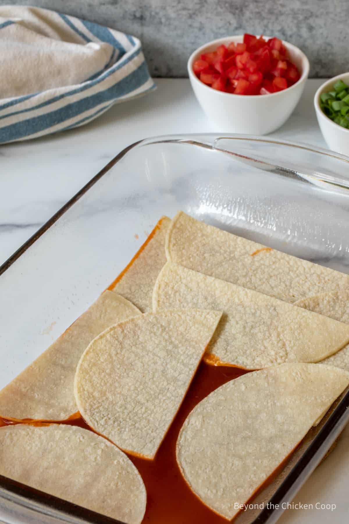 Layering a casserole with tortillas.