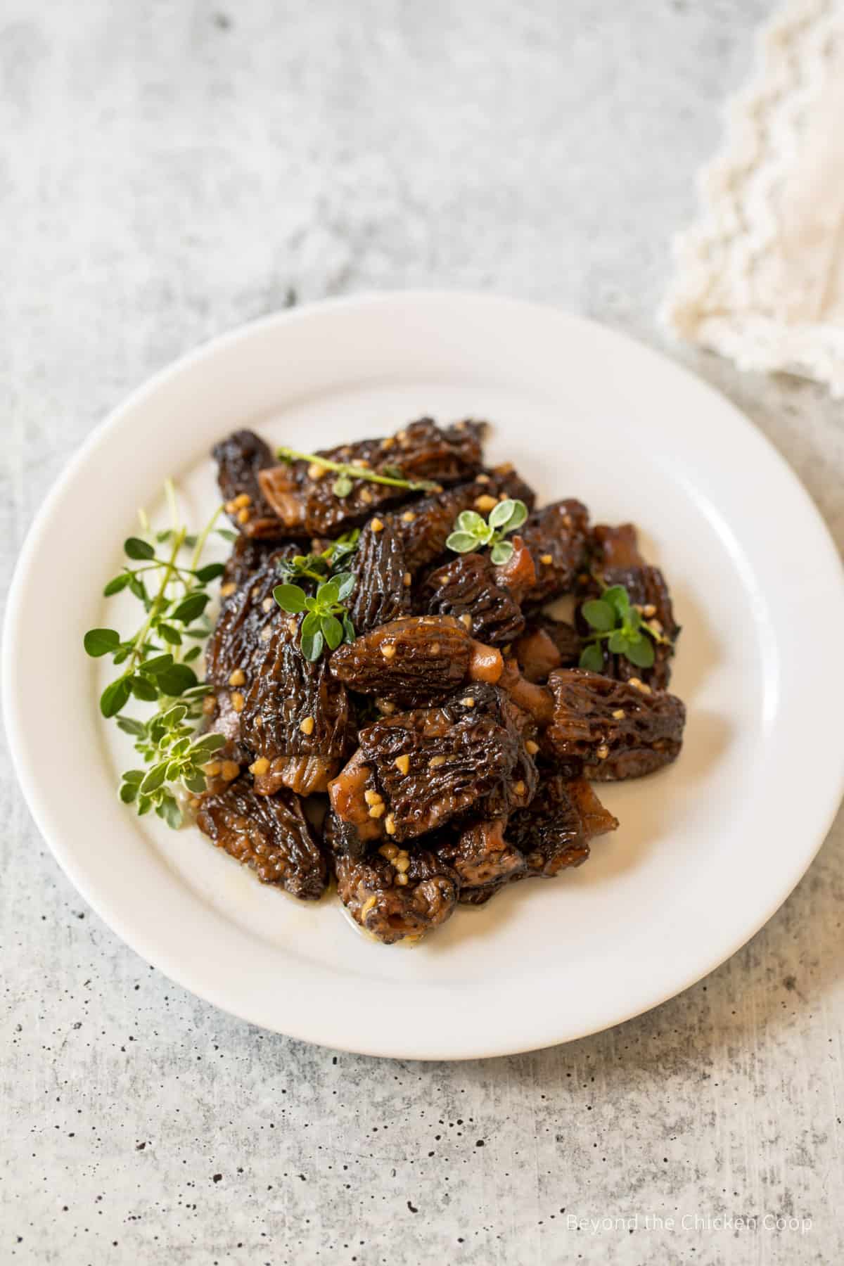Cooked morels on a plate with fresh thyme.