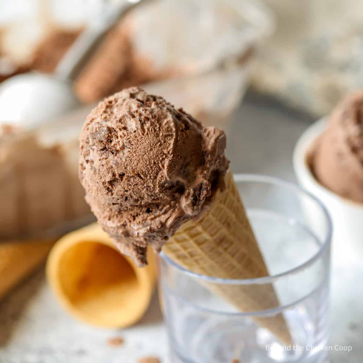 A scoop of chocolate ice cream in a sugar cone. 