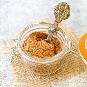 A small container filled with a seasoning blend with an ornate spoon in the mixture.