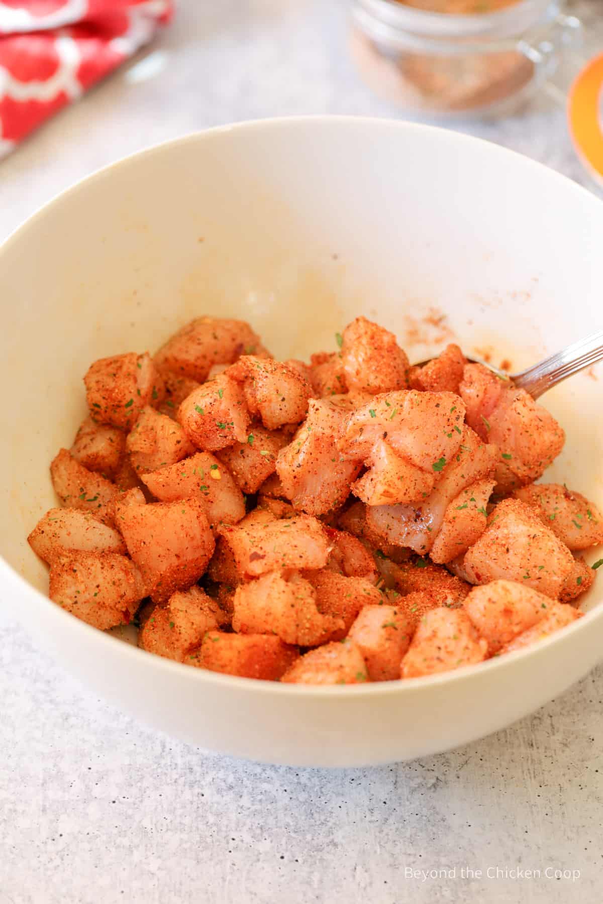 Cut raw chicken covered with seasoning in a bowl.