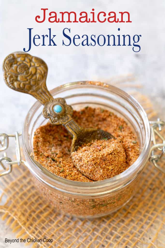 A small glass filled with seasoning and a spoon.