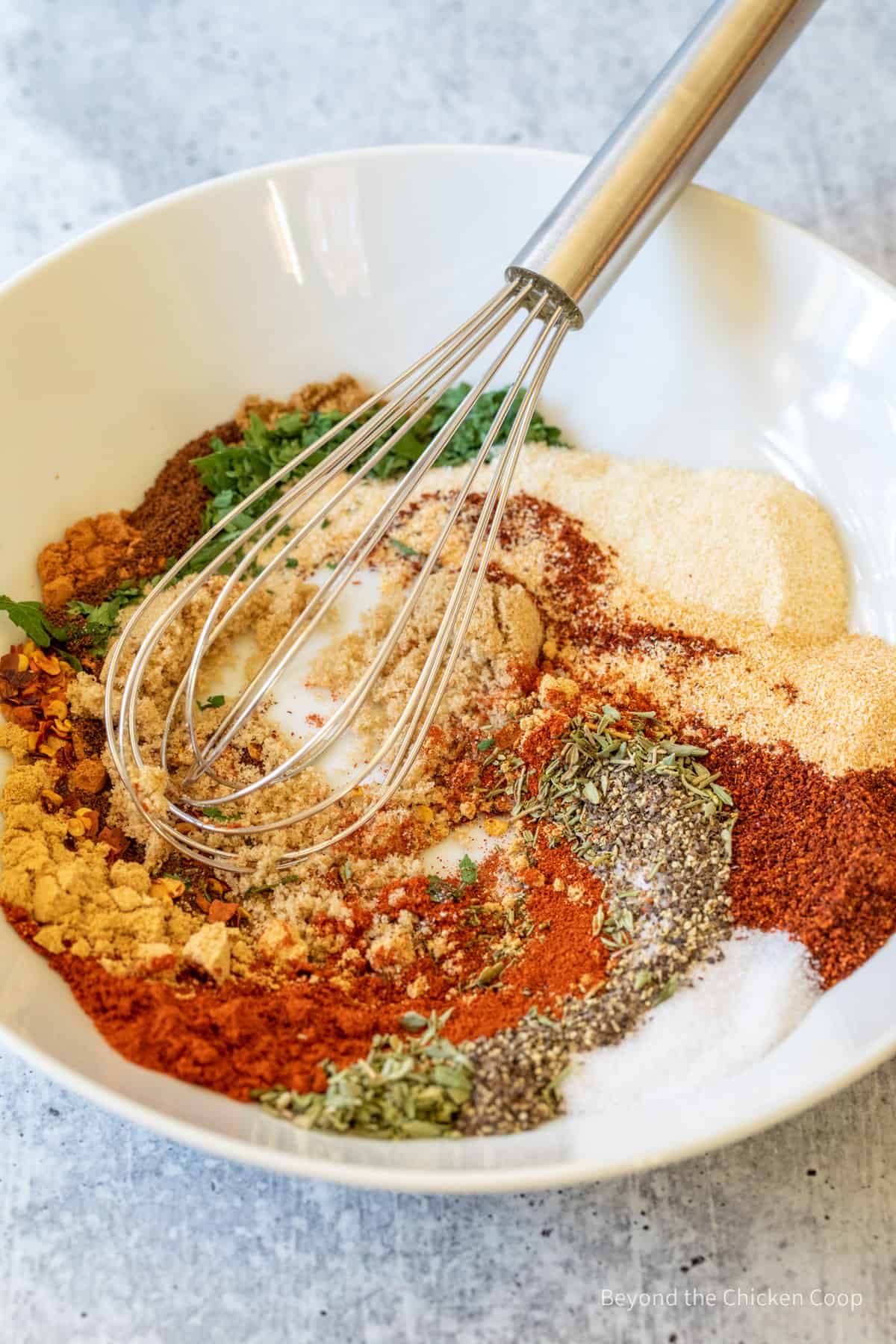 Swirling spices together in a bowl with a whisk.