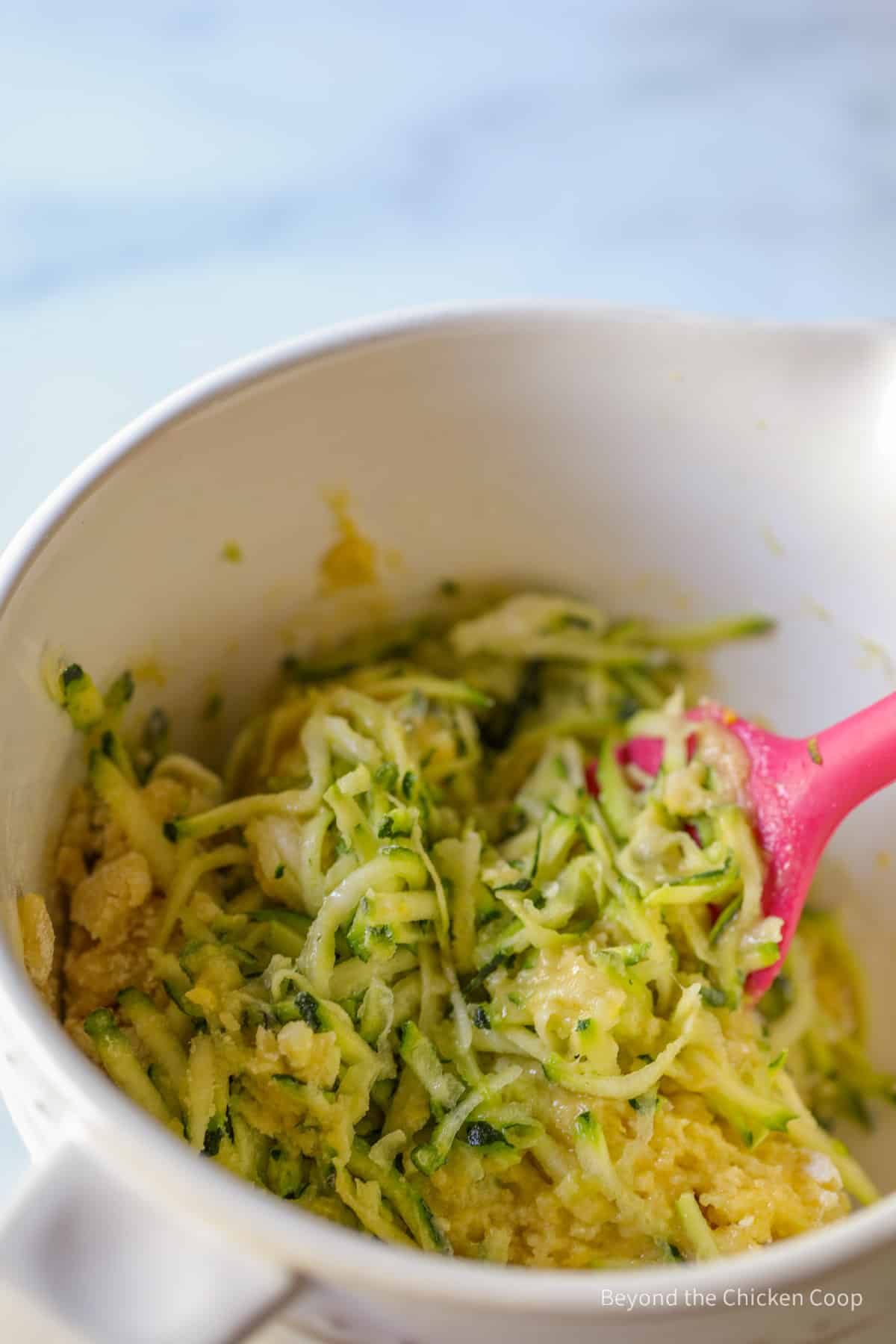 Mixing in grated zucchini into batter.