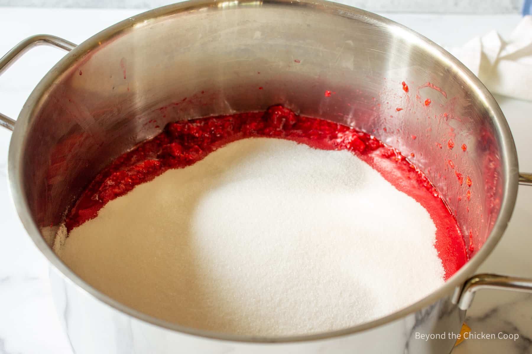 A pot filed with raspberries and sugar.