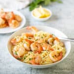 Shrimp on top of pasta in a bowl.