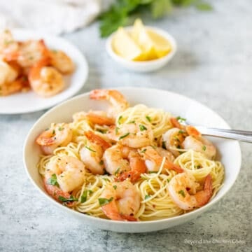 Shrimp on top of pasta in a bowl.