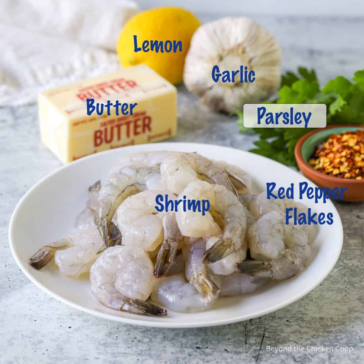 Raw shrimp in a bowl next to other ingredients.