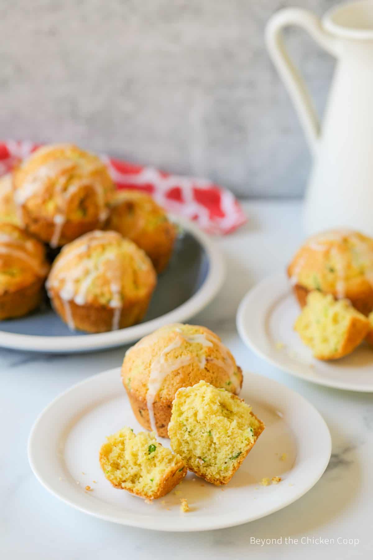 A zucchini muffin cut in half on a plate.