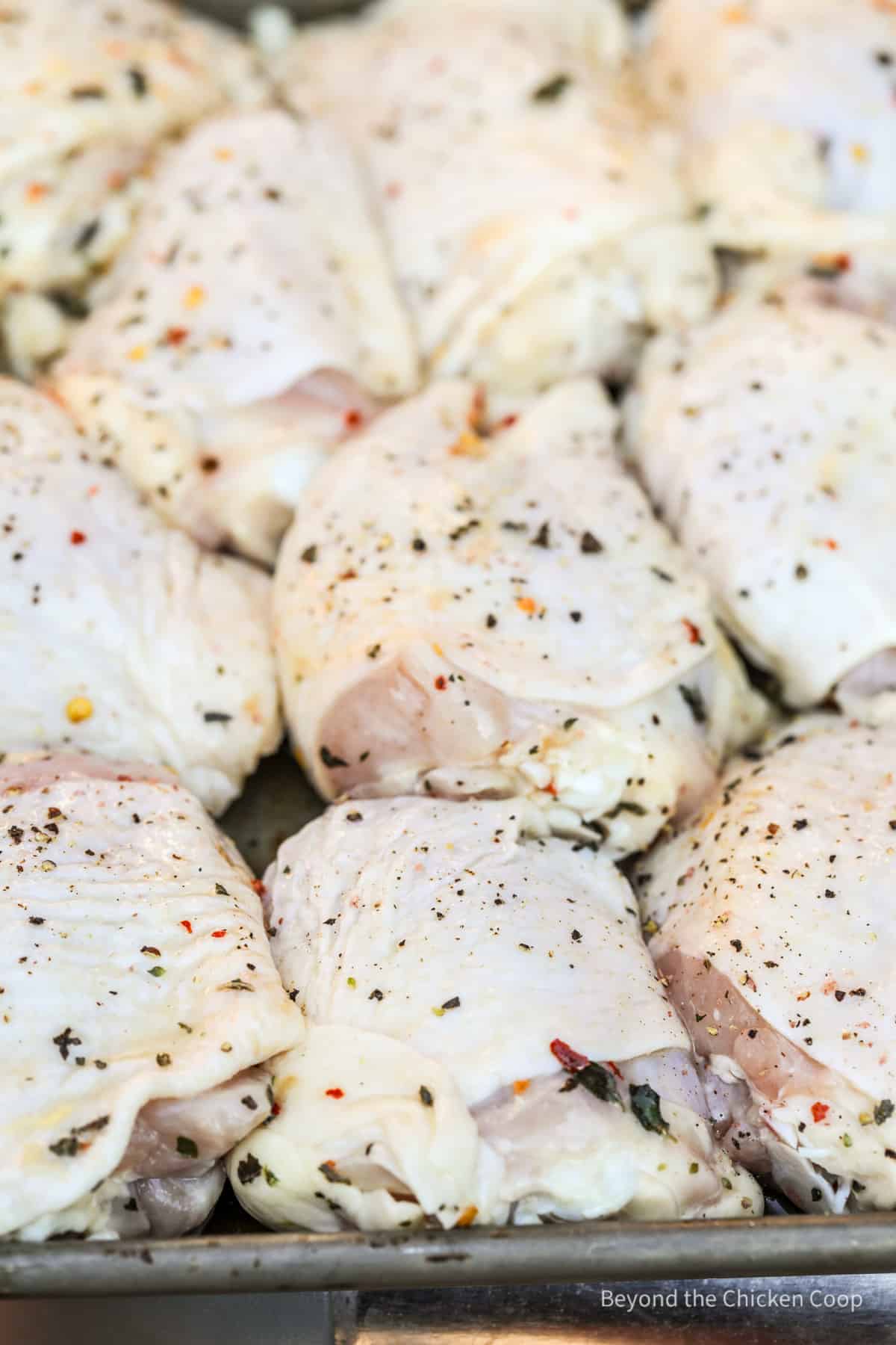 Uncooked chicken thighs on a baking sheet.