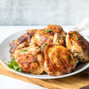 Grilled chicken thighs on a white plate.