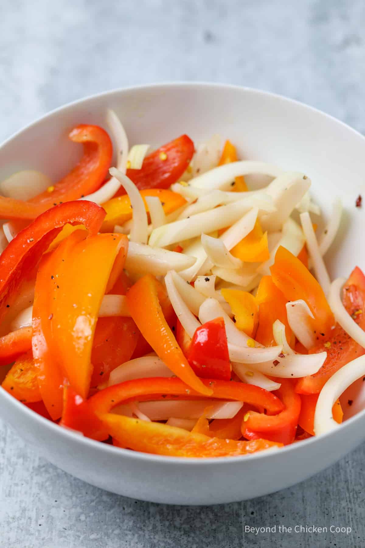 Sliced peppers and onions in a bowl.