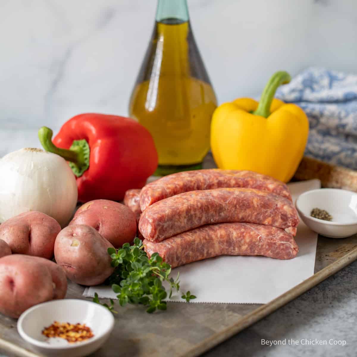 Italian sausage next to potatoes, onions, and bell peppers. 