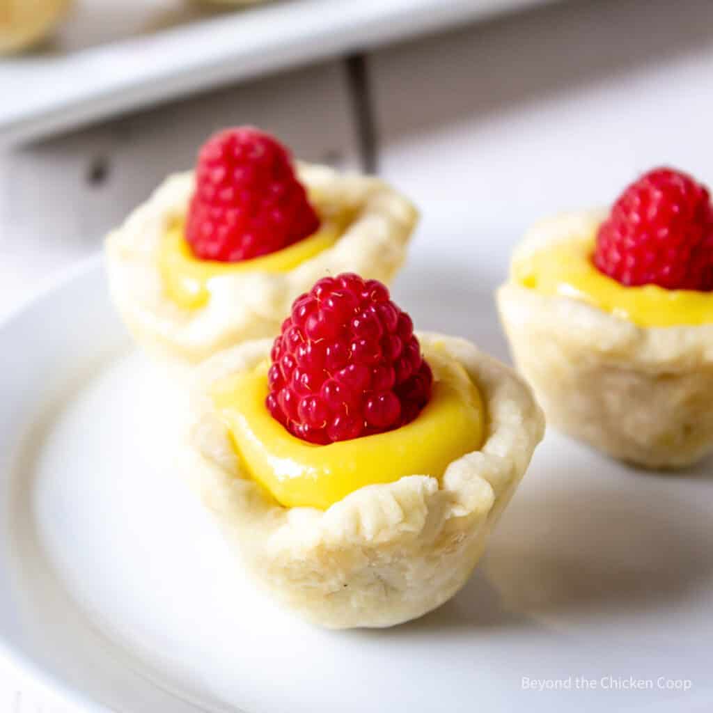 Mini tarts filled with lemon curd and topped with a raspberry.