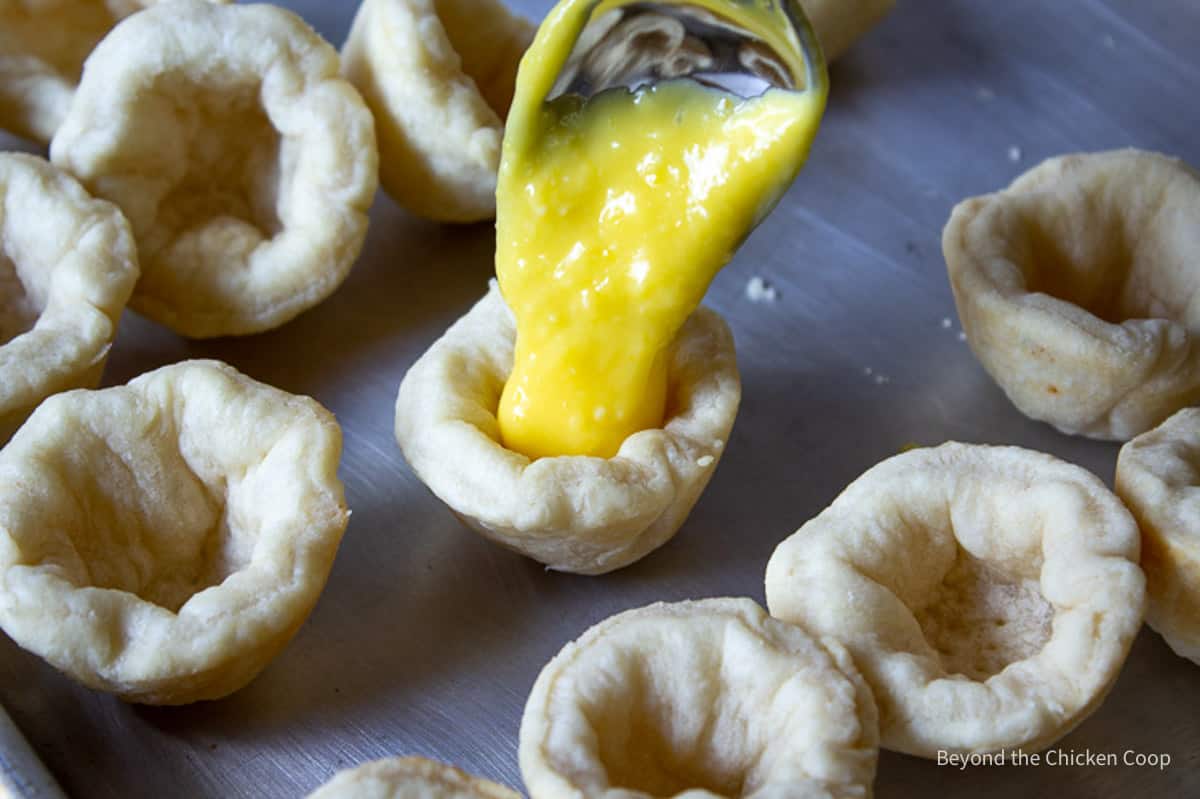 Filling mini pie shells with lemon curd.