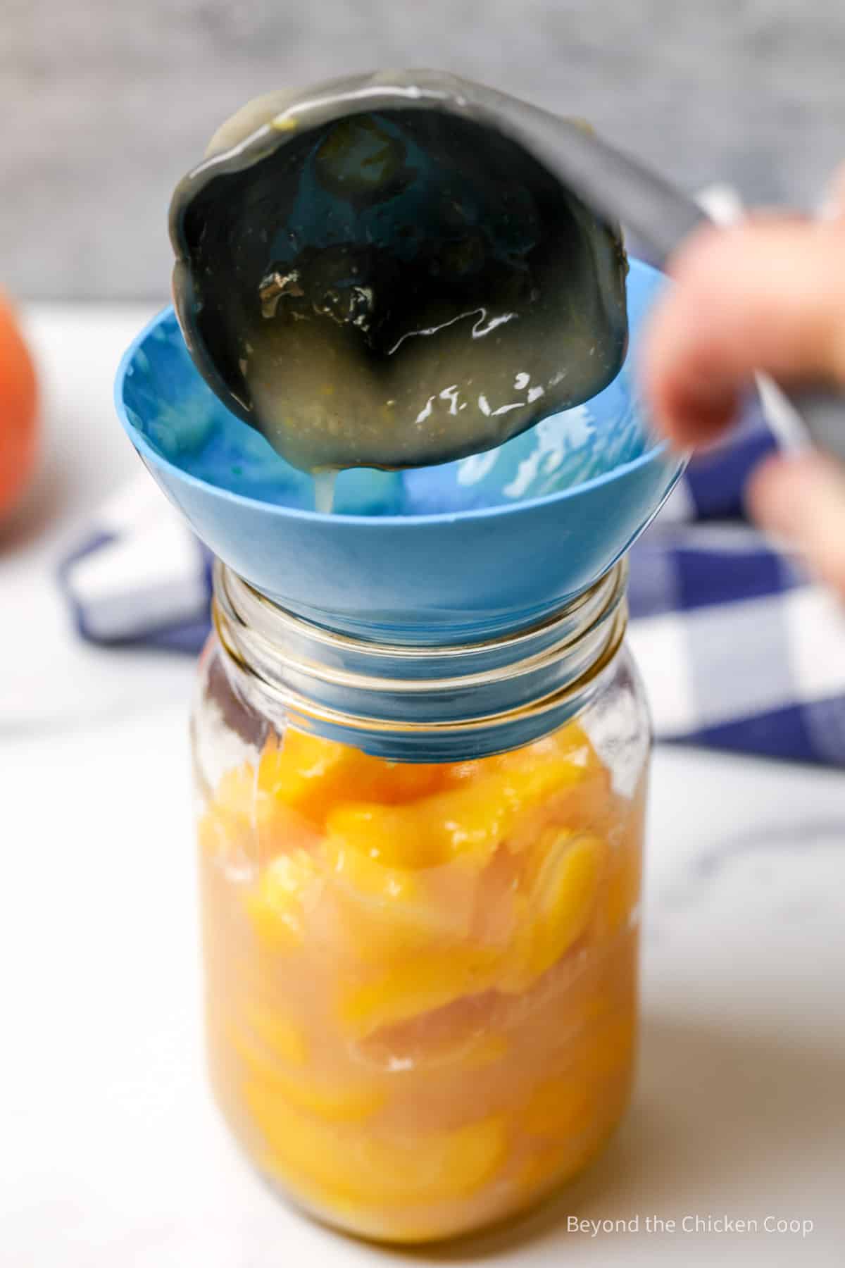 Pouring peach filling into a quart sized jar.
