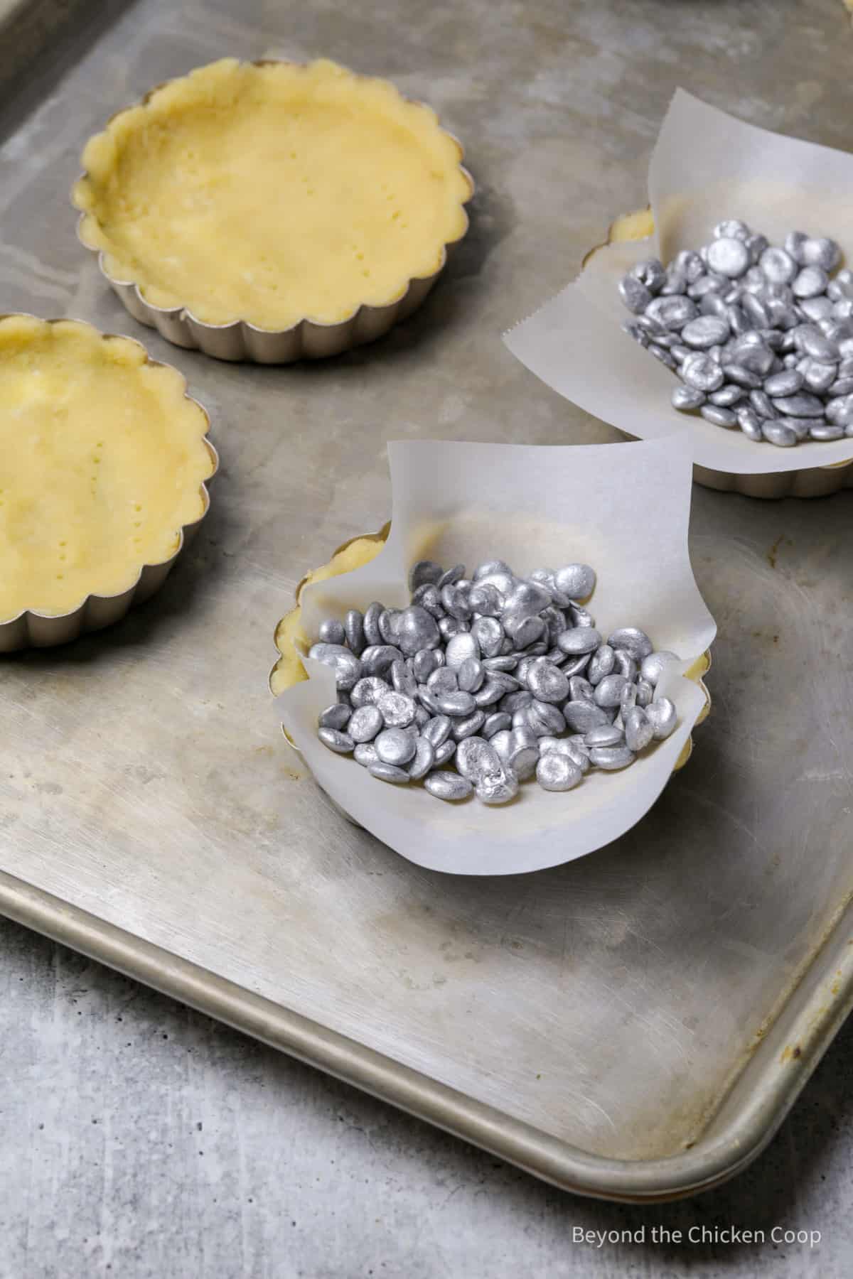 Pie weights in tart shells lined with parchment paper. 