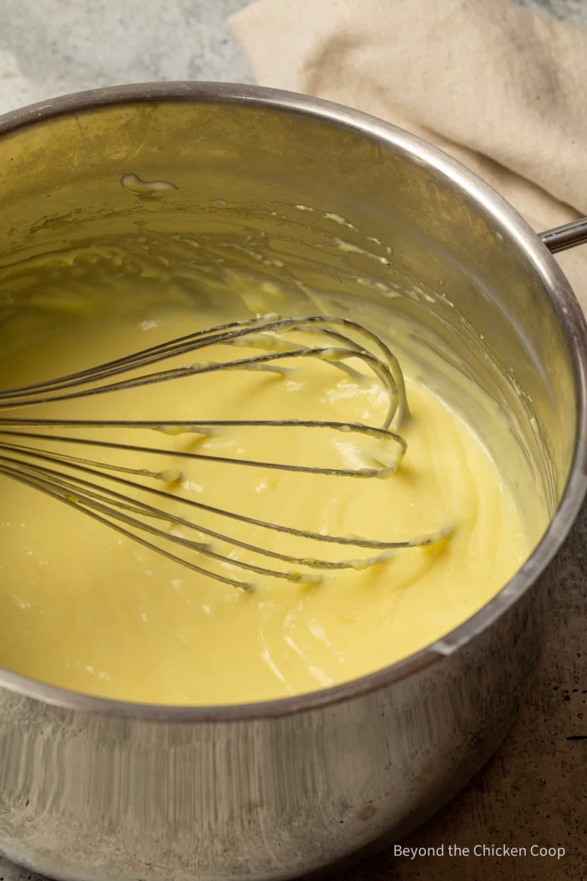 Pastry cream in a pot with a whisk.