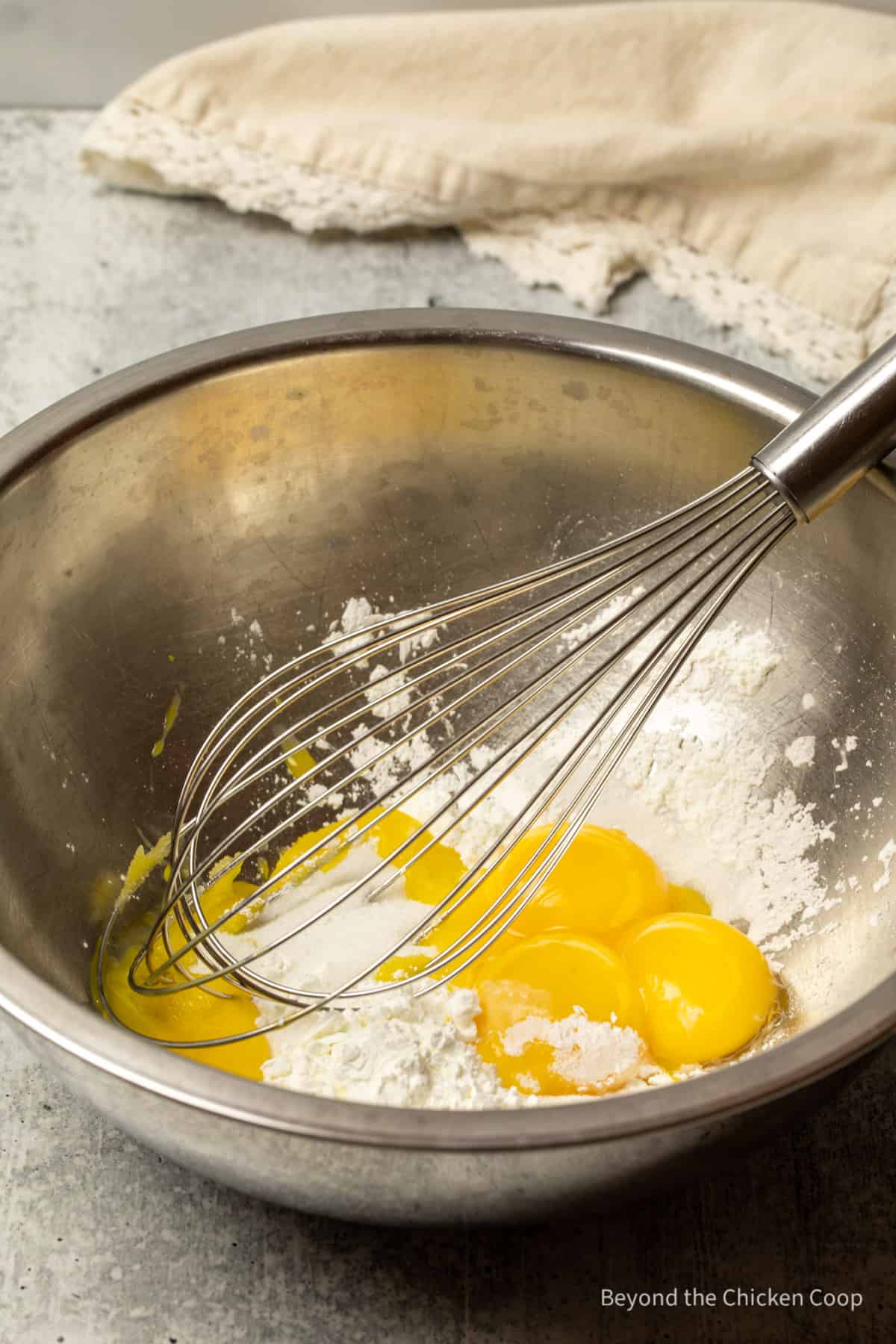 Egg yolks being mixed in a bowl with a whisk.