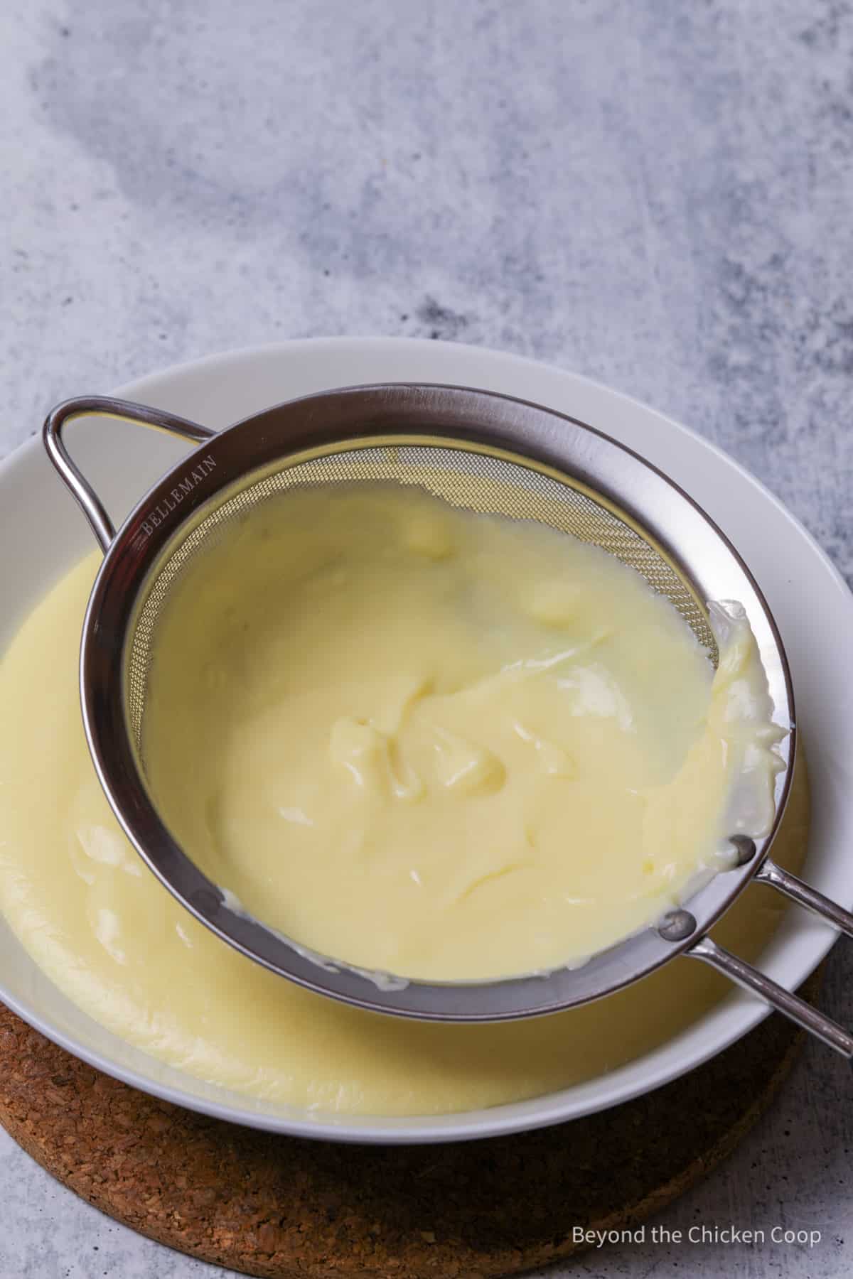 Straining pastry cream through a sieve.