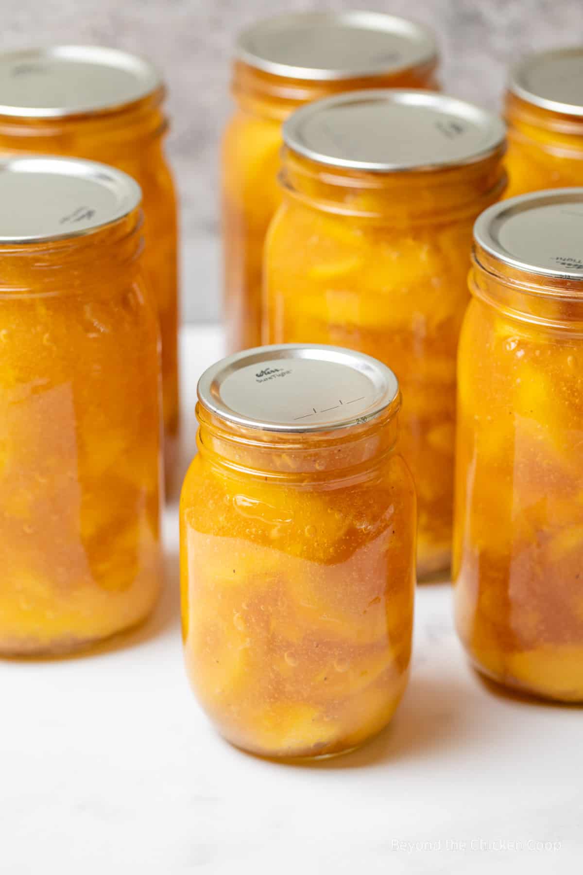Canning jars filled with a pie filling with peach slices. 