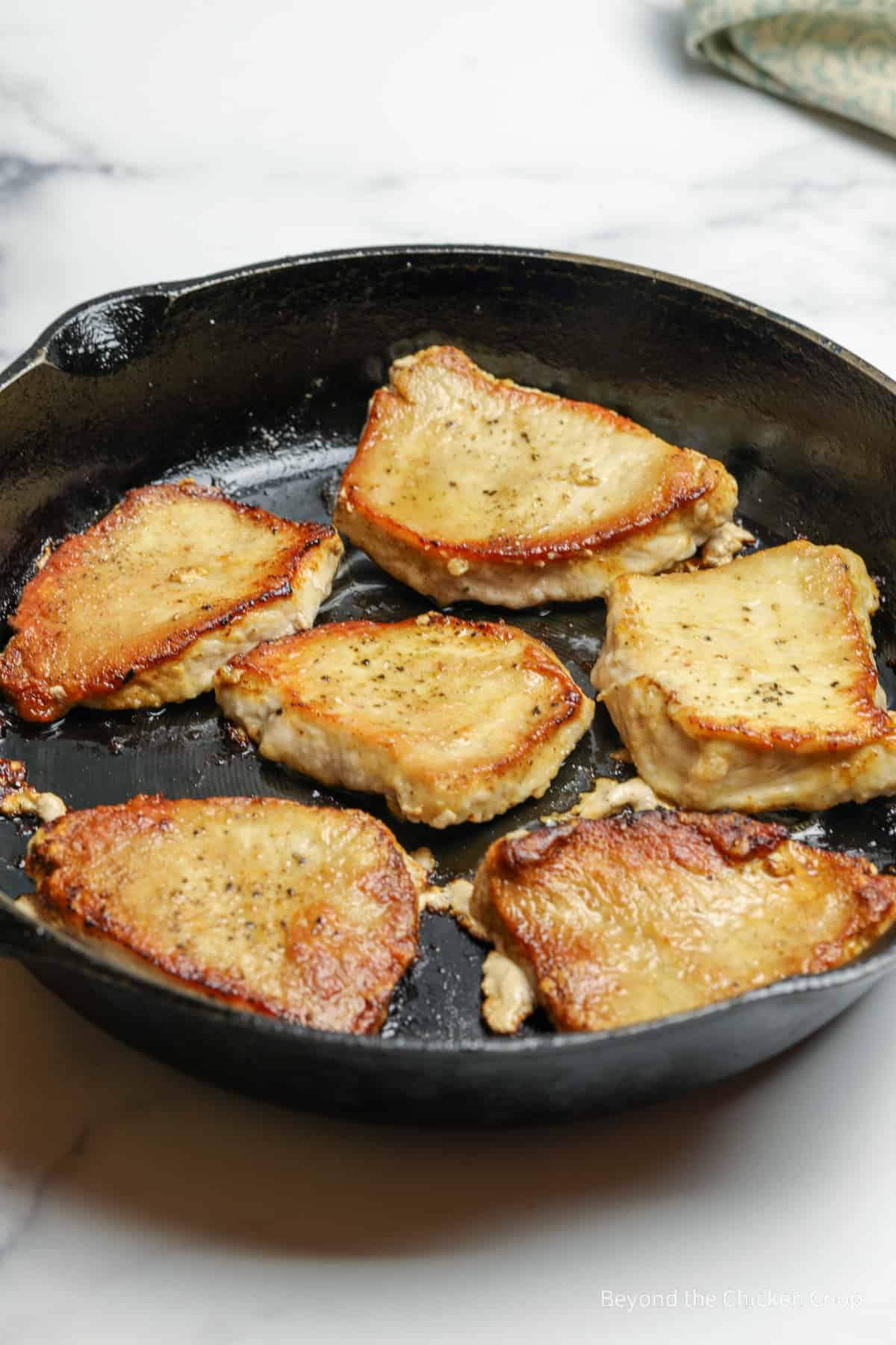 Brown pork chops in a cast iron skillet.