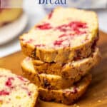 Slices of a breakfast bread with raspberries stacked on a board.