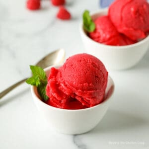 Scoops of raspberry sorbet in small white bowls.