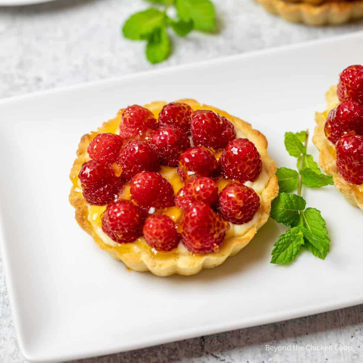 A small tart topped with fresh raspberries. 
