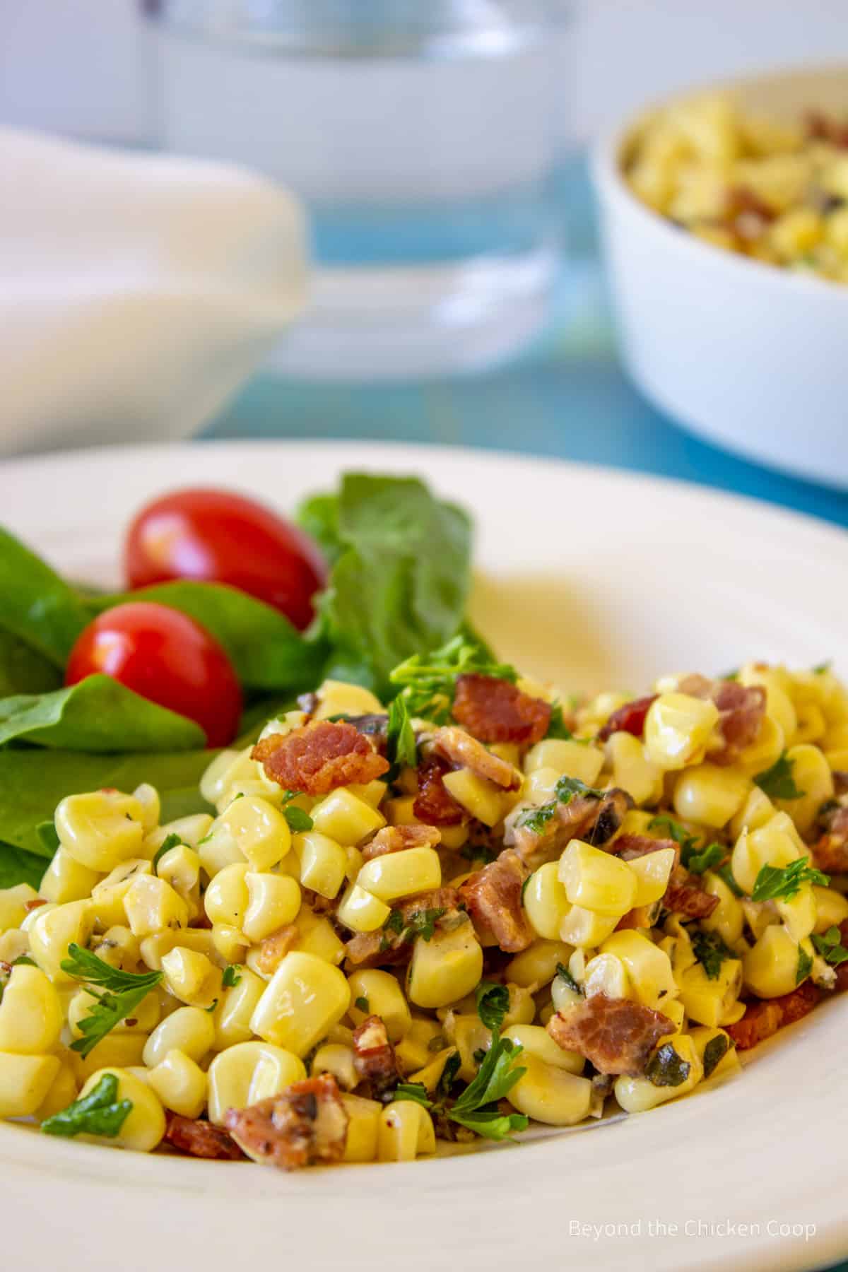 A plate with corn with bits of bacon and herbs.