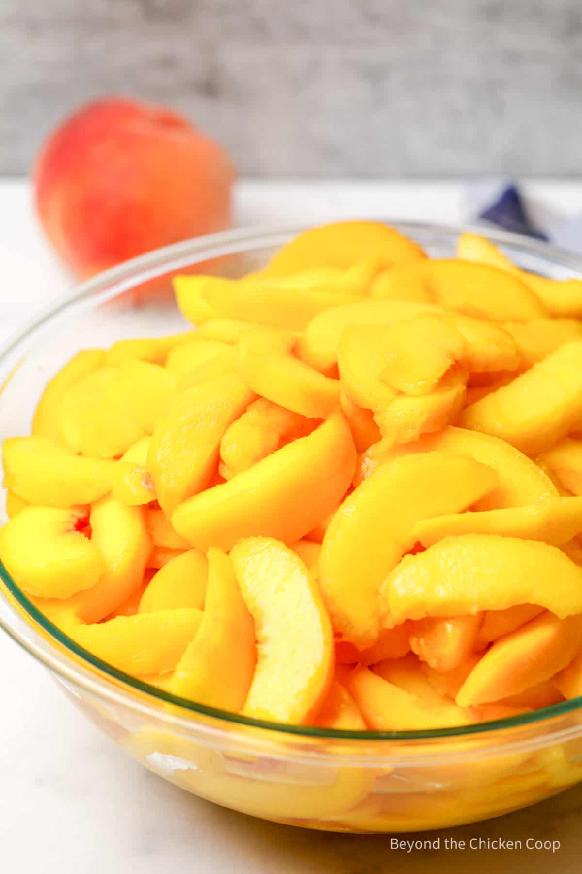 A large glass bowl filled with sliced peaches.