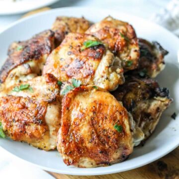 Crispy chicken thighs on a white plate.