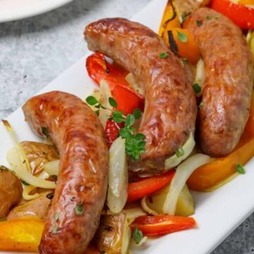 Italian sausages on top of onions, peppers and potatoes.