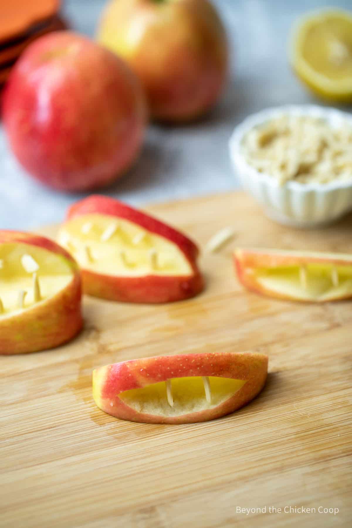 A sliced apple filled with slivered almonds making a mouth shape.