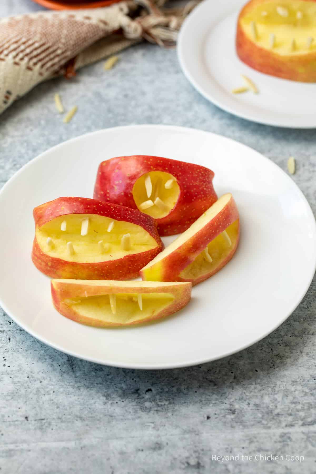 A white plate filled with apple wedges shaped as mouths. 