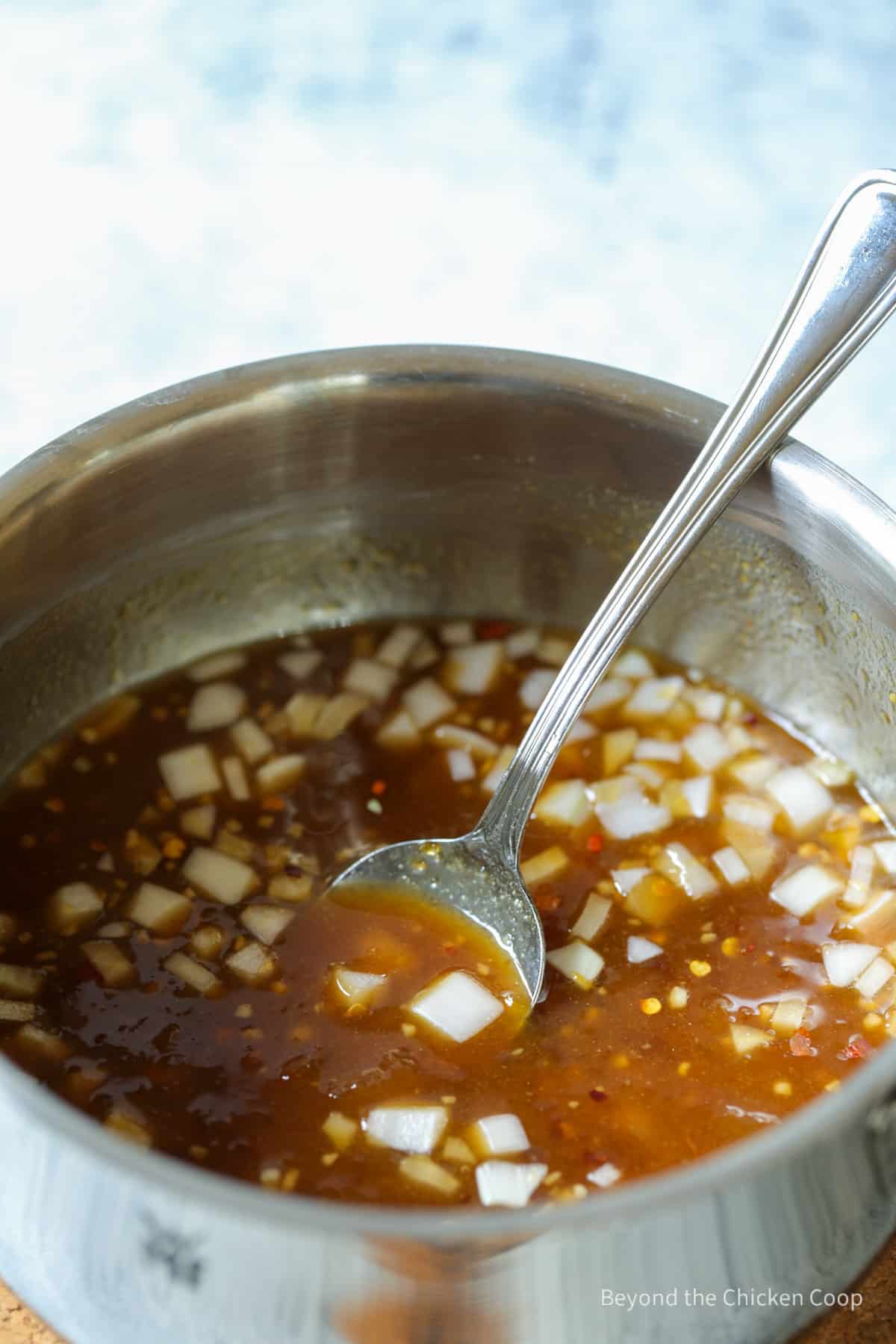 An apricot sauce in a pan with a spoon.