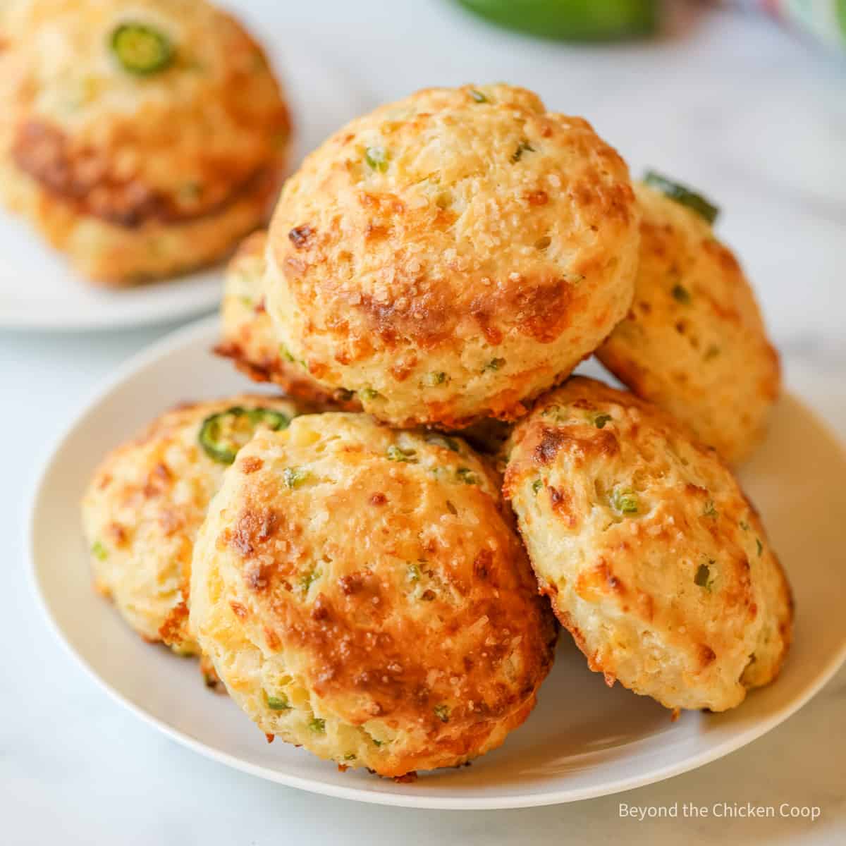 A plate filled with biscuits filled with bits of jalapeno. 