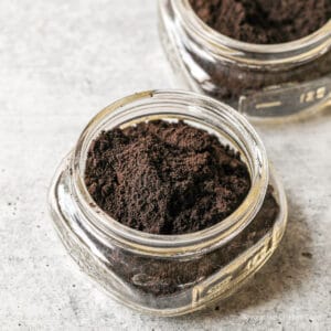 A glass jar filled with finely ground coffee.