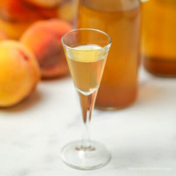 A small glass filled with a peach beverage.