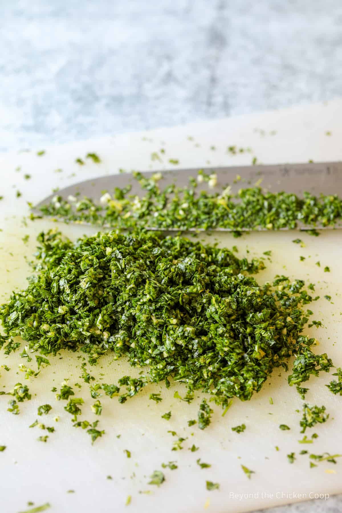 Italian gremolata on a cutting board with a knife.