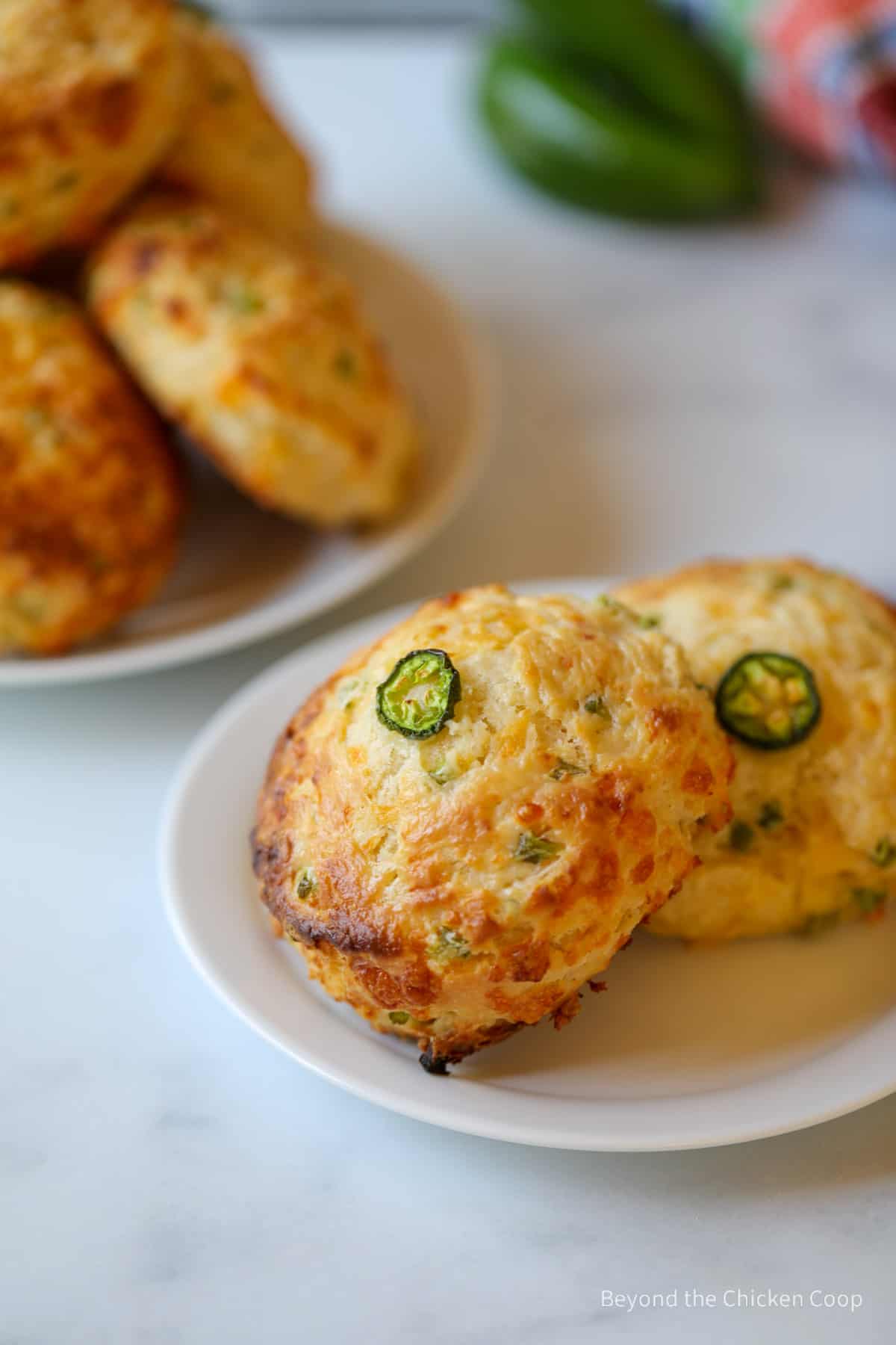 Biscuits topped with sliced jalapenos on a small plate.