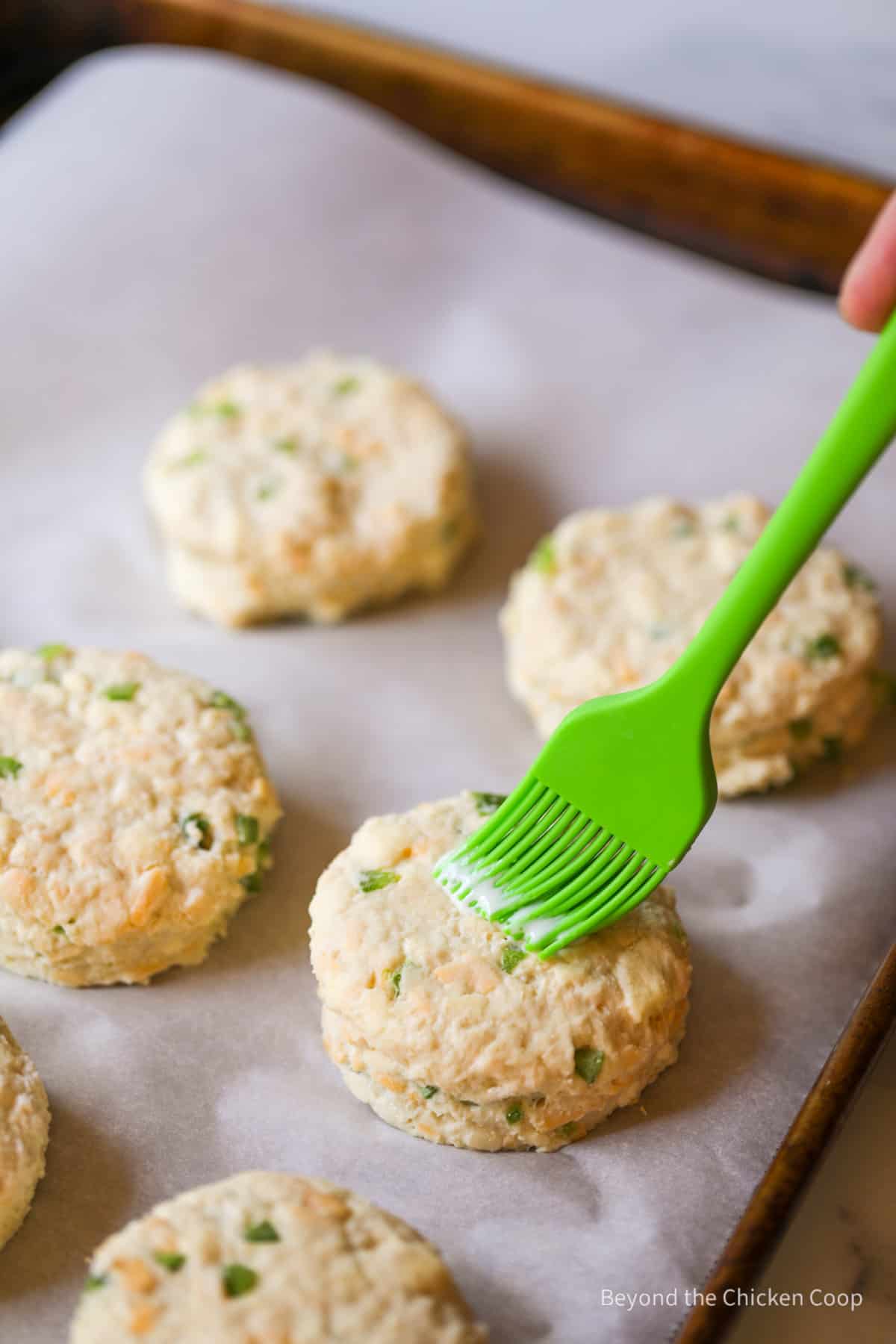 Brusing the top of biscuits with milk.