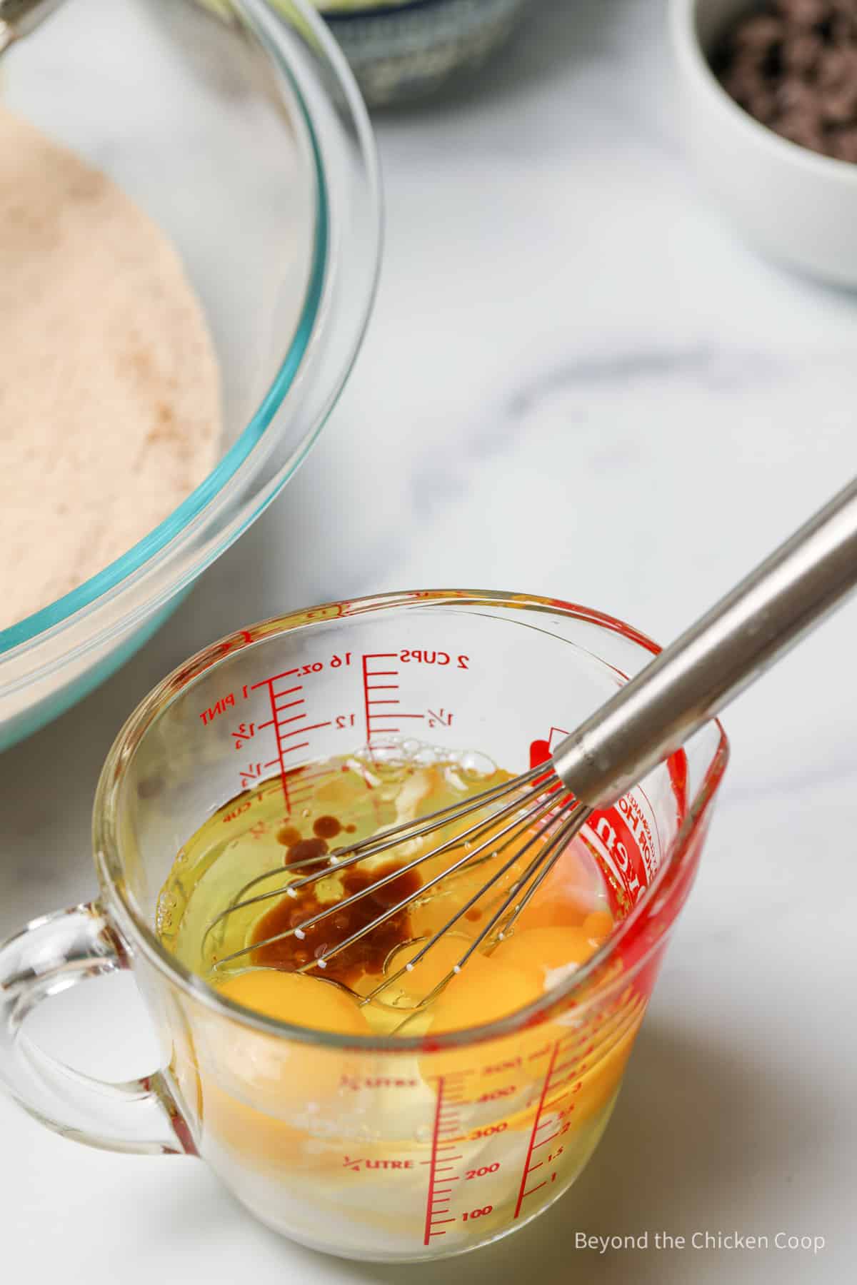 Mixing eggs, sour cream and oil together in a glass measuring cup.