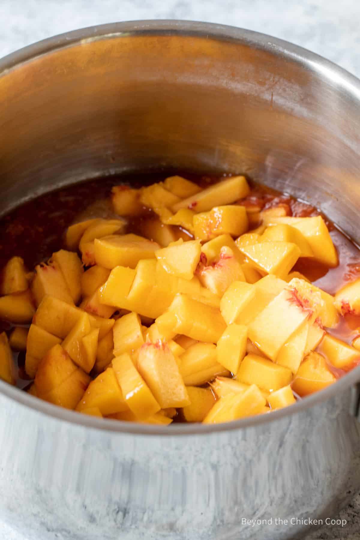 Chopped peaches with a red sauce in a pan. 