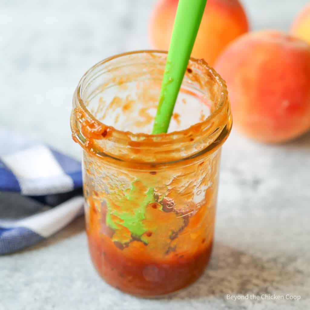 A jar partially filled with a barbecue sauce.