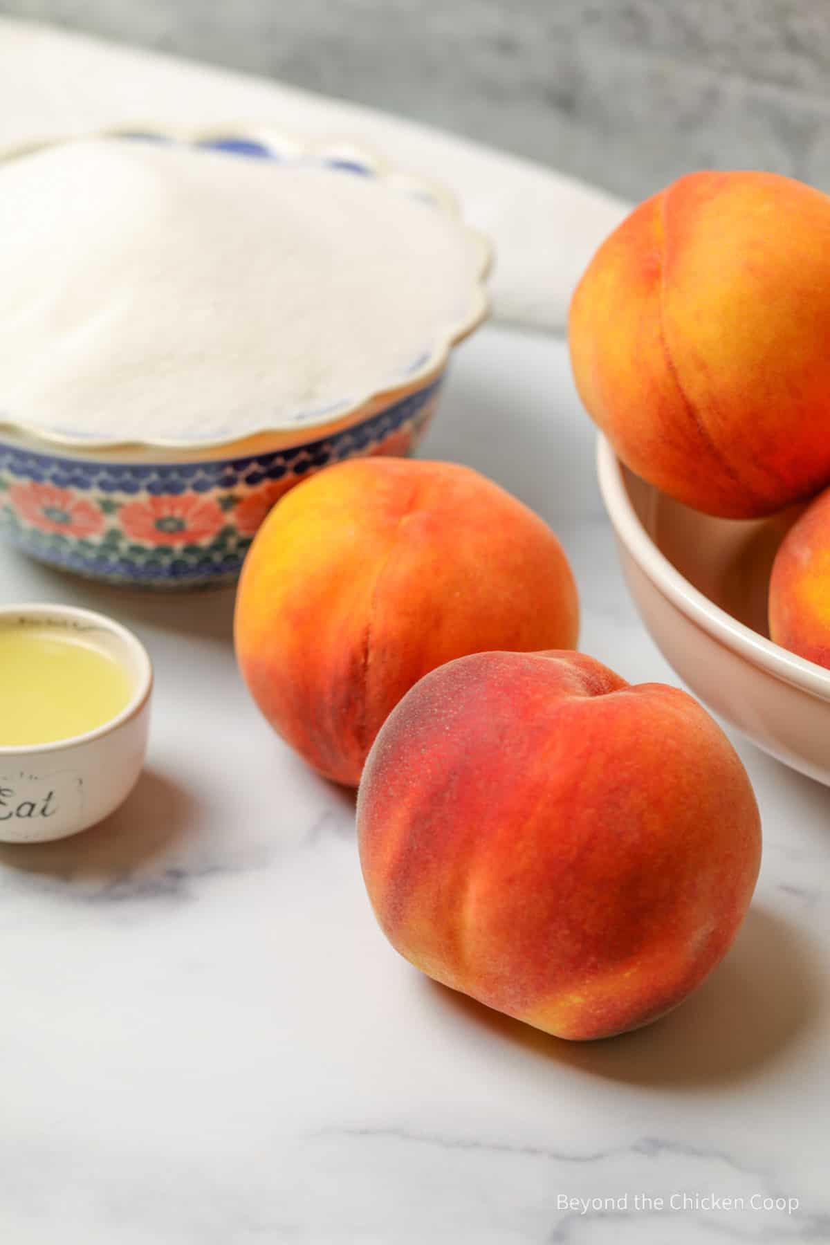 Fresh peaches and a bowl of sugar.